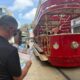 Visitor reading an Aruba Discovery guide map near the red Aruba streetcar in downtown Oranjestad